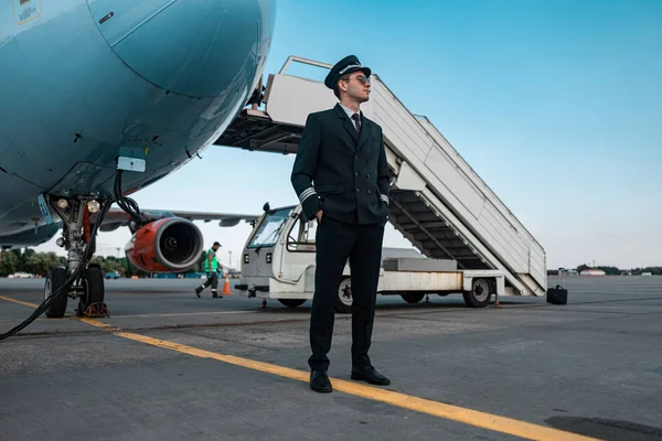 Havaalanında birine bakan üniformalı sakin erkek pilot