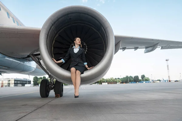 Mooie jonge vrouw zittend in de buurt van motor van het vliegtuig — Stockfoto
