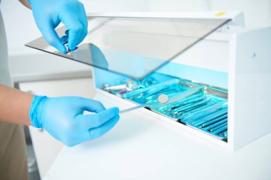 Diş hekimi klinikte sterilizasyon için aletler hazırlıyor