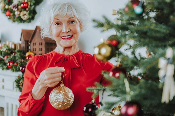 Šťastná starší dáma stojí s vánoční hračkou — Stock fotografie