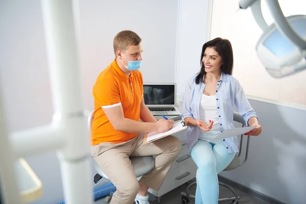 Glückliche Dame im Gespräch mit Zahnarzt im Zimmer — Stockfoto