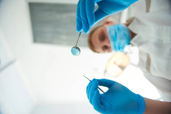 Estomatologista adulto profissional está segurando ferramentas dentárias — Fotografia de Stock