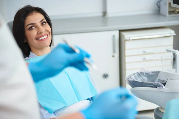 Jovem feliz olhando para o dentista e sorrindo — Fotografia de Stock