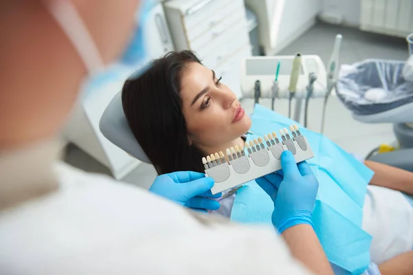 Dentista sosteniendo corona dental a dama feliz — Foto de Stock