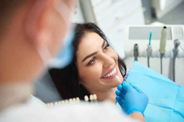 Estomatólogo masculino sosteniendo corona dental para mujer sonriente — Foto de Stock