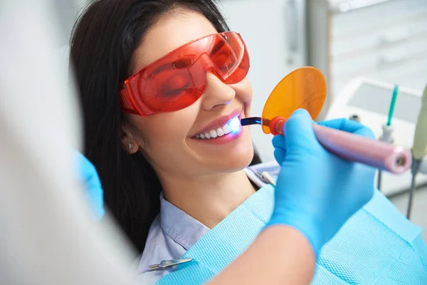 El estomatólogo está usando lámpara dental en la clínica —  Fotos de Stock