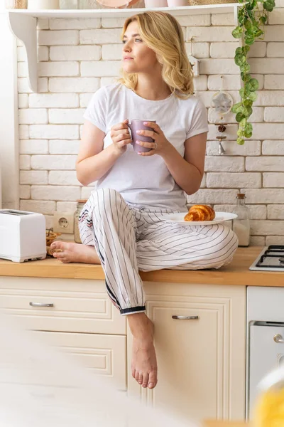 Mujer bastante joven sentada en la cocina con taza — Foto de Stock