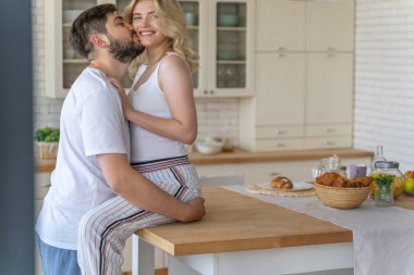 Sakallı adam evde güzel bir kadın öpüyor