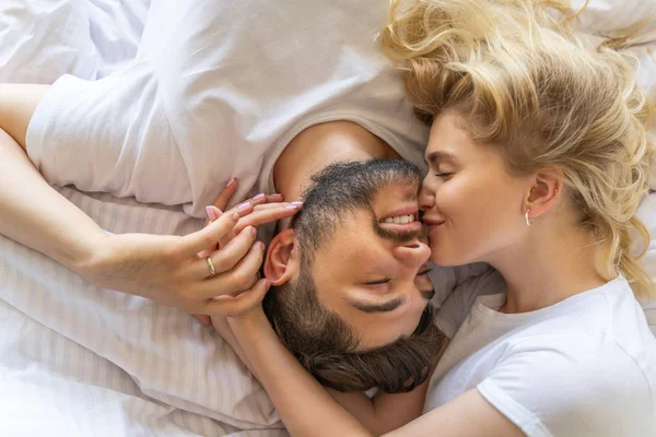 Pretty young female is kissing man in bed — Stock Photo, Image