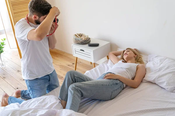Ładna młoda kobieta pozowanie aparatu fot w łóżku — Zdjęcie stockowe