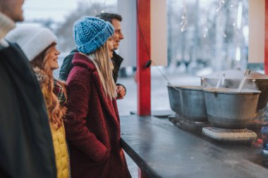 Neşeli gençler sıcak içecekler satın almak için gidiyor