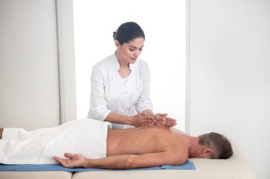 Kadın masaj terapisti terapötik sırt masajı yapıyor