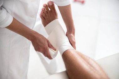 Doktor ayağına bandaj takıyor.