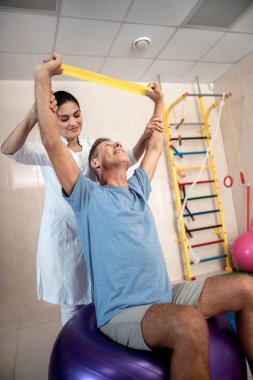 Erkek hasta fintes topu üzerinde oturuyor