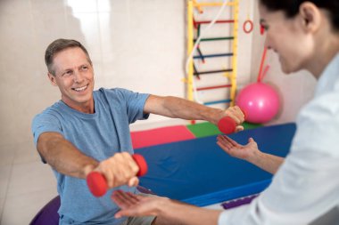 Adam dambıllarla önünde el ele tutuşuyor.