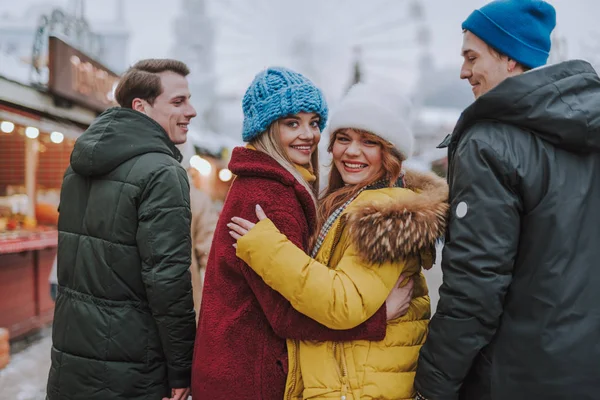Mutlu genç dişiler eşlerinin arasında duruyorlar.