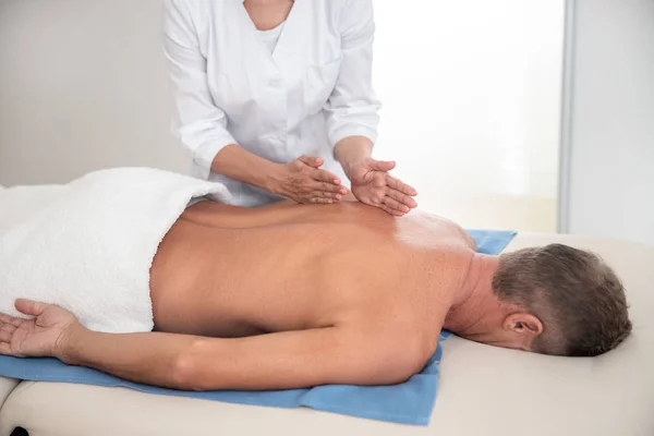 Doctor Holding hand på ryggen under massage — Stockfoto