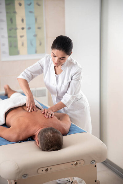 Доктор давит пальцами на мужскую спину.
