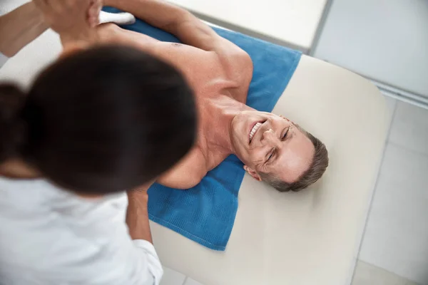 Šťastný muž ležící na masážním stole v nemocnici — Stock fotografie