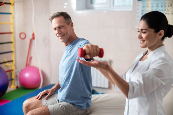 Happy male patient holding a dumbbell in hand