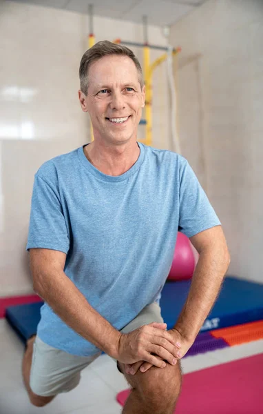 Happy adult man is stretching legs in room