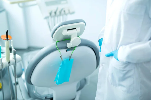 Стоматолог в стерильных перчатках стоит рядом со стулом стоматолога — стоковое фото