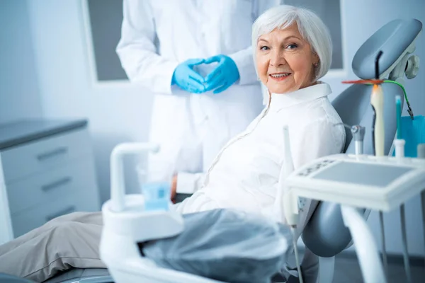 Šťastná dospělá žena sedí v zubařské židli — Stock fotografie