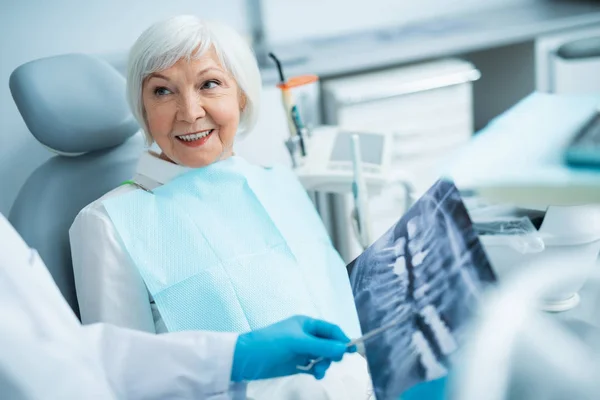 Šťastná dospělá žena sedí v zubařské židli — Stock fotografie