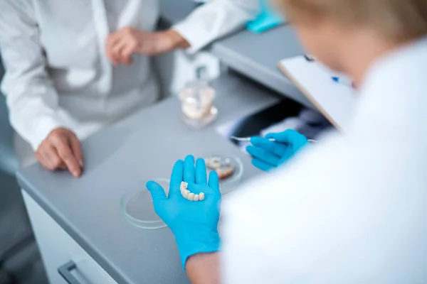 Dentista feminina mostrando dentaduras para um paciente — Fotografia de Stock