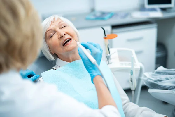 Dentista feminina está tratando dentes para paciente — Fotografia de Stock