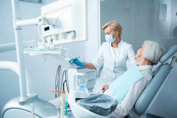 Señora sonriente con los ojos cerrados acostada en la silla dental — Foto de Stock