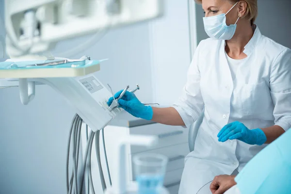 Estomatóloga en guantes estériles sosteniendo instrumento dentista — Foto de Stock