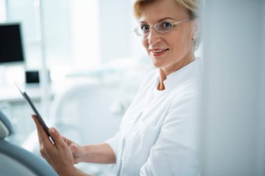 Mutlu diş hekimi diş ofisinde tablet tutuyor