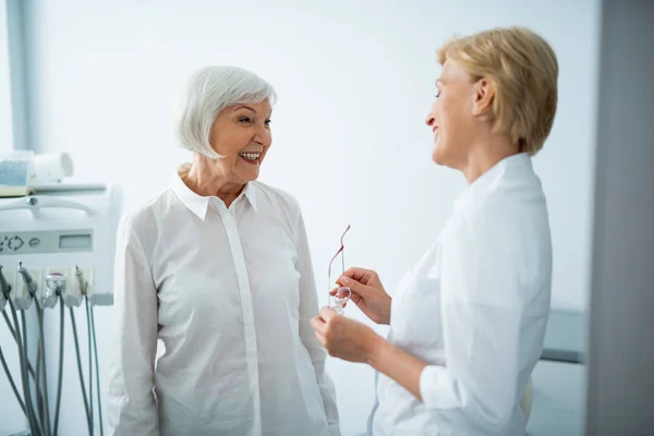 Odontólogo sonriente con paciente en clínica dental — Foto de Stock