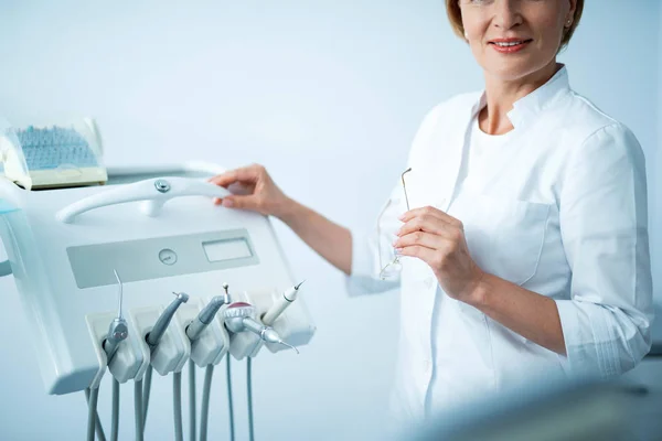 Dentista feminina está de pé no consultório odontológico — Fotografia de Stock