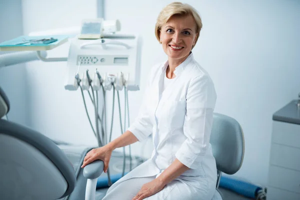 Un médecin souriant est assis dans une clinique dentaire — Photo