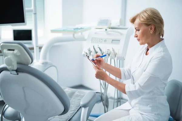 Feliz dentista está sentado en la clínica dental — Foto de Stock