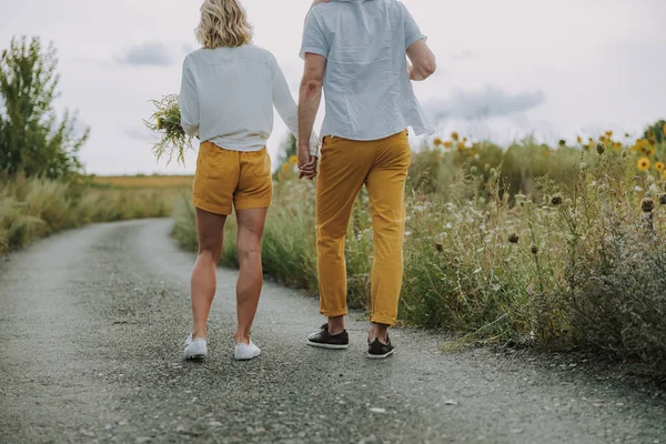 Calma padres jóvenes tomados de la mano en el camino al aire libre — Foto de Stock