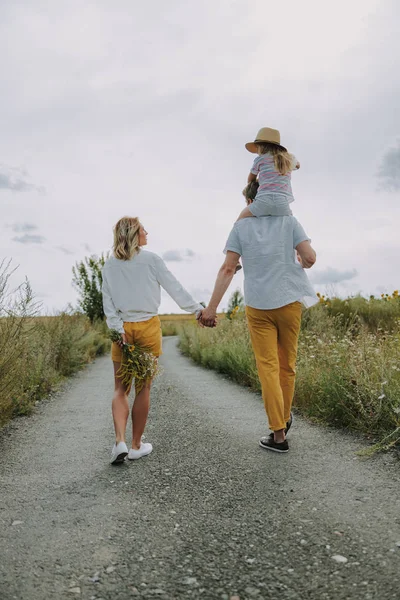 Красивая блондинка с цветами гуляет со своей семьей — стоковое фото