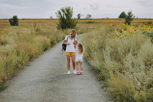 Kleine Kaukasische meisje wandelen met moeder op de weg buitenshuis — Stockfoto