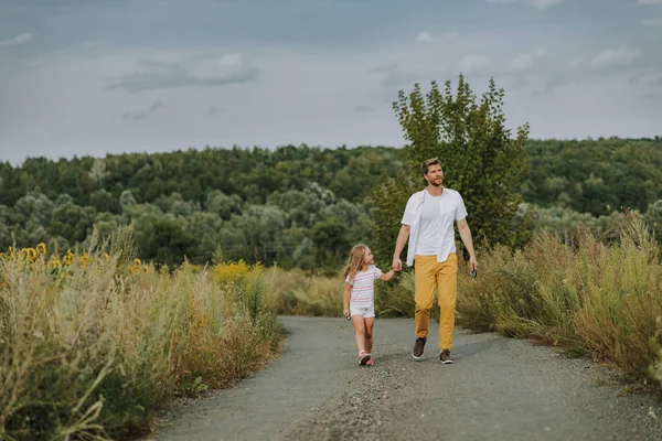 Menina caucasiana pequena andando com o pai na estrada ao ar livre — Fotografia de Stock