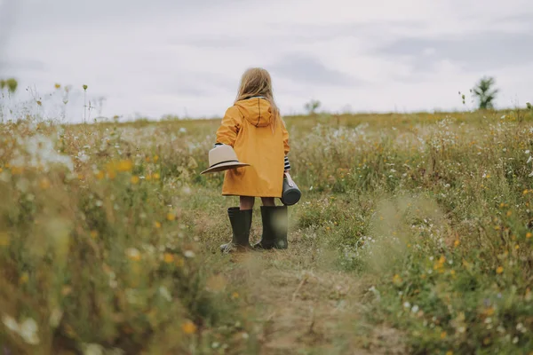 Niña en impermeable está sosteniendo sombrero al aire libre —  Fotos de Stock