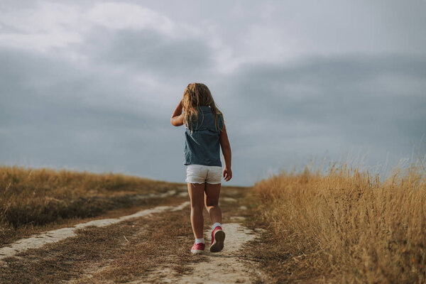 Little kid is having stroll on the field