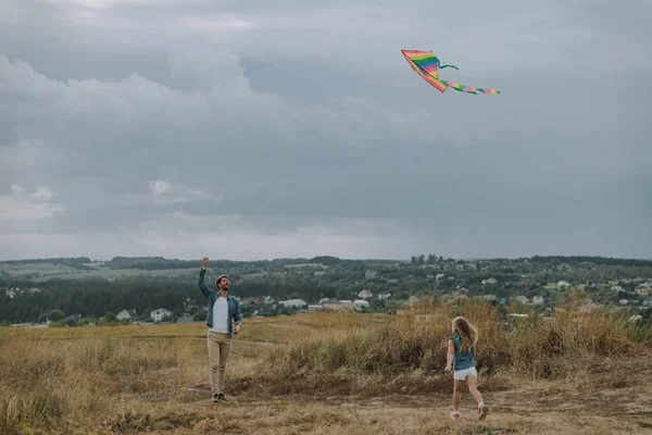 Jonge vader lanceert een vlieger op veld — Stockfoto