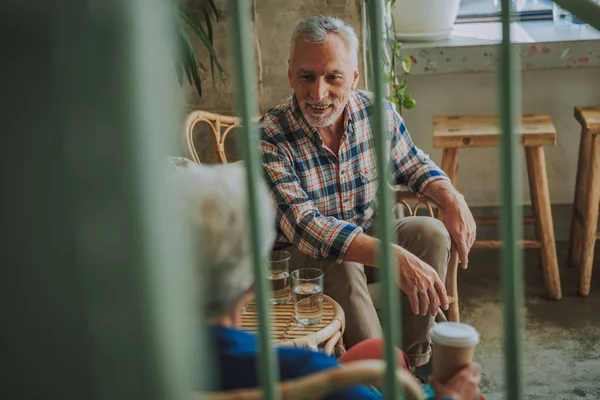 Friendly mature man smiling to friend in cafe stock photo — Stock Photo, Image