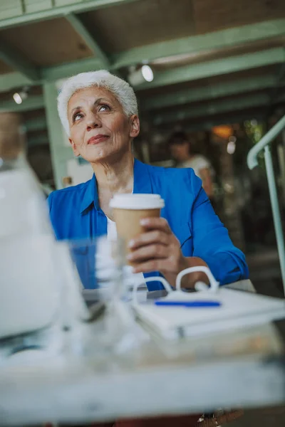 Продумана жінка з кавою дивиться вгору стокове фото — стокове фото
