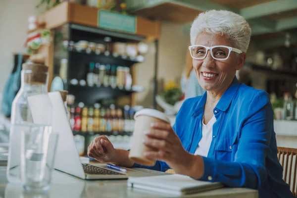 Mujer madura positiva con café en café foto de stock — Foto de Stock