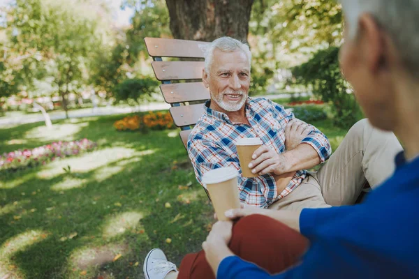 Hombre sonriente en el parque escuchando a la mujer stock foto — Foto de Stock