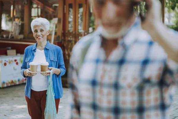 Mujer sonriente sosteniendo café para ir foto de stock — Foto de Stock