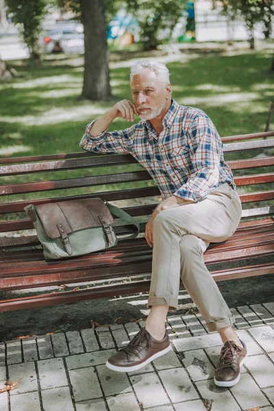 Doordachte man met tas zittend in Park Stock Photo — Stockfoto